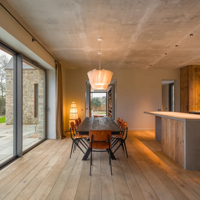 Dining area with pendant light, timber table and exposed concrete ceiling at dusk