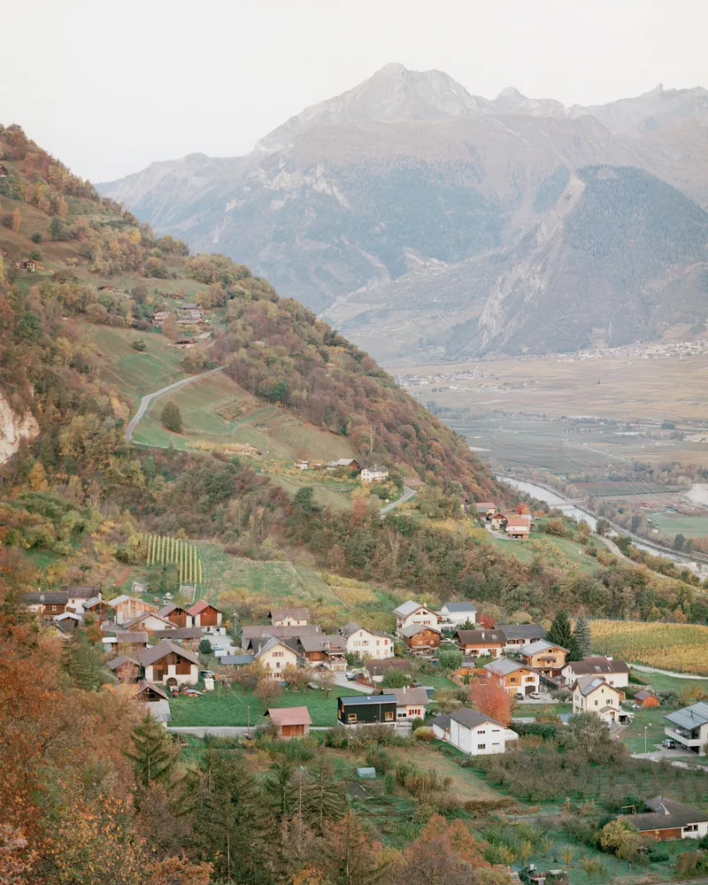 Village scattered on a terraced hillside in an alpine valley at dusk
