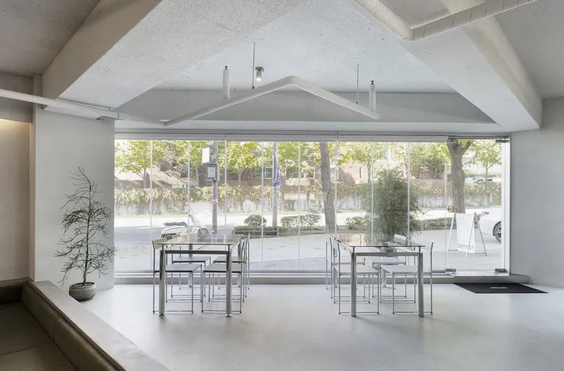 Vaulted ceiling space with wide storefront glazing framing trees and pedestrians along the street