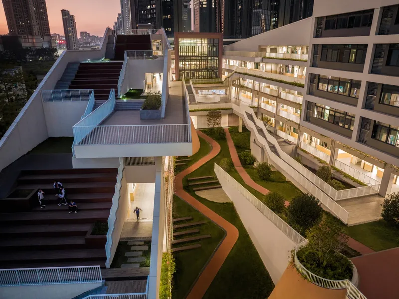 Aerial view of terraced rooftop courtyard with curved pathways and planted beds at dusk