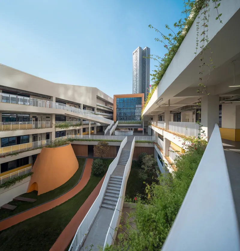 Pedestrian bridge crossing between planted terraces with climbing vines on white columns