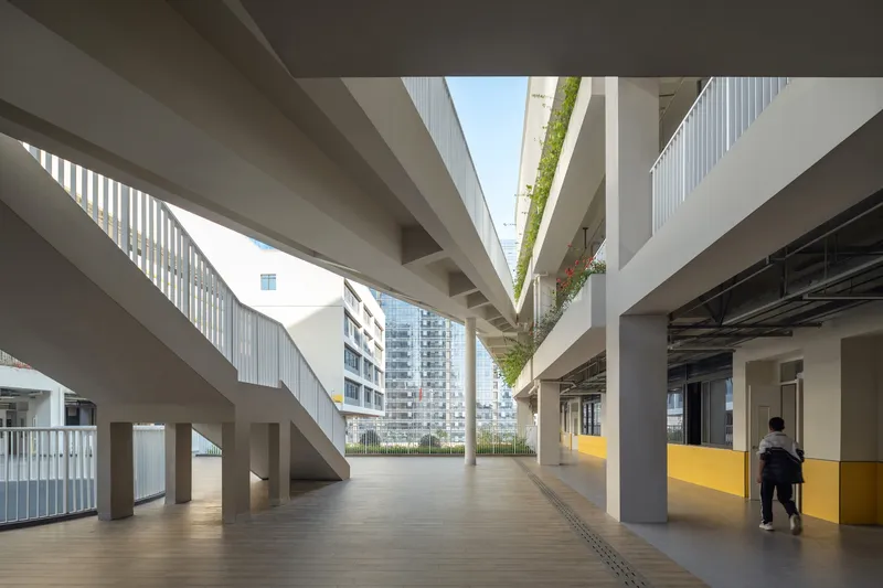 Covered walkway with diagonal cross-bracing and vertical planted wall under open sky