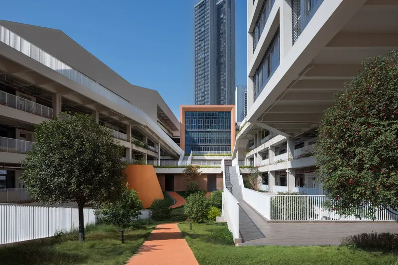 Central courtyard with curved pathways linking residential blocks under a clear blue sky