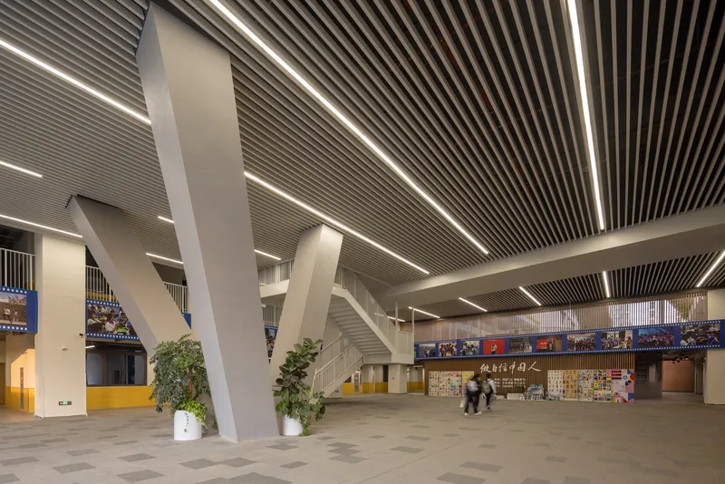 Entrance hall with angled white columns and a linear slatted ceiling with integrated lighting