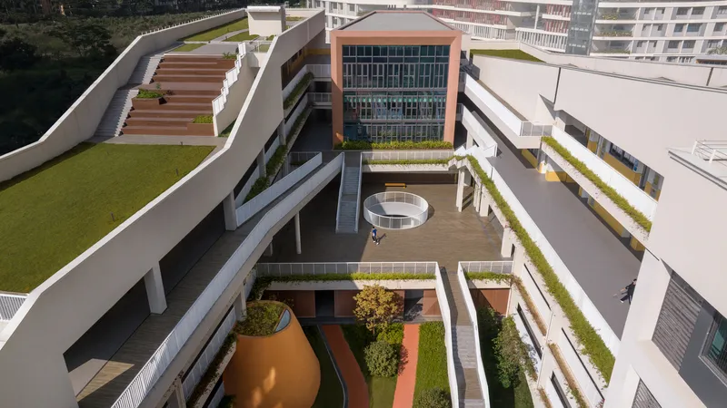 Courtyard view from above showing a circular pavilion and terraced planters between classroom wings