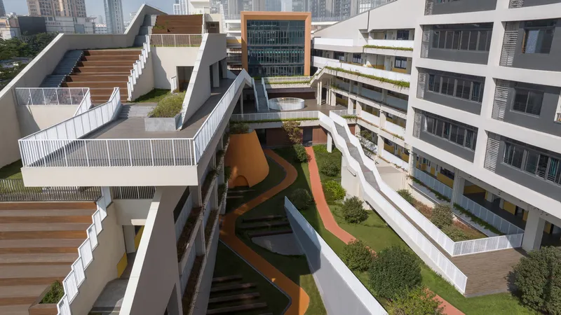 Sloped green terraces connecting white classroom wings with louvered facades