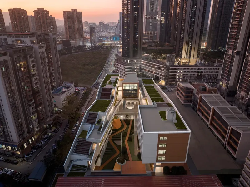 Elevated view of the illuminated campus at dusk nestled between residential towers