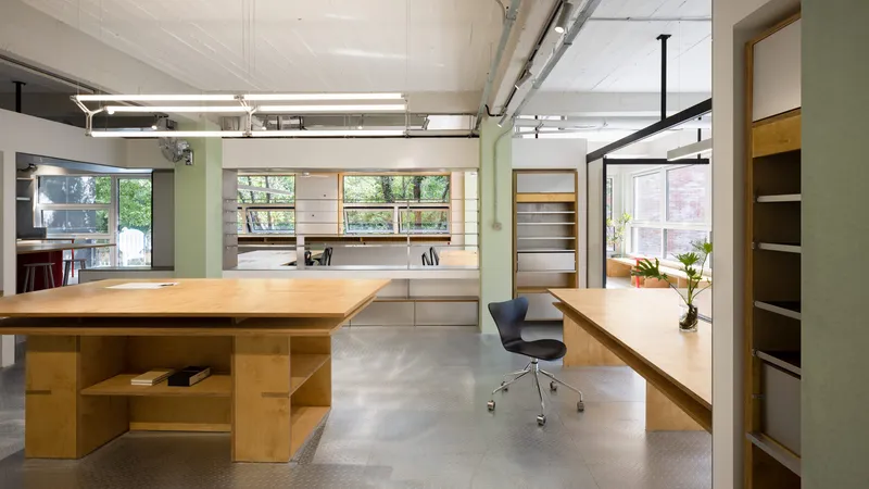 Timber desks with integrated storage beneath exposed ductwork and suspended linear lighting fixtures