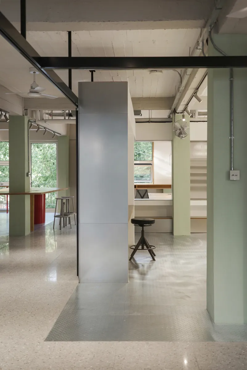 Mezzanine walkway with black steel railings above terrazzo floor and freestanding grey column