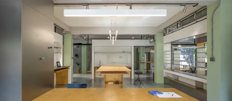 Open office interior with pale green partitions, plywood workstations and exposed ceiling skylight