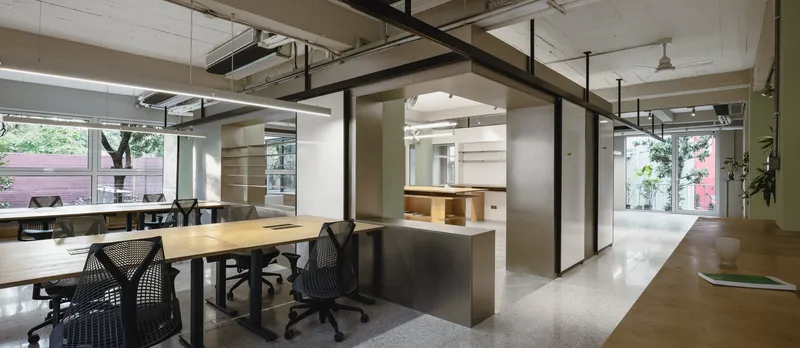 Long view through the office showing frosted partitions dividing workspaces with terrazzo flooring