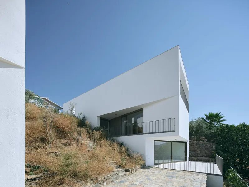 White stucco facade with recessed balconies and terrazzo terrace overlooking dry scrubland