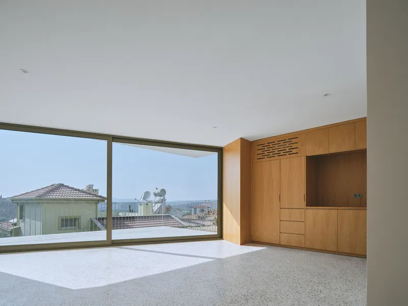 Interior living space with floor-to-ceiling window and built-in wood cabinetry with louvered upper panels