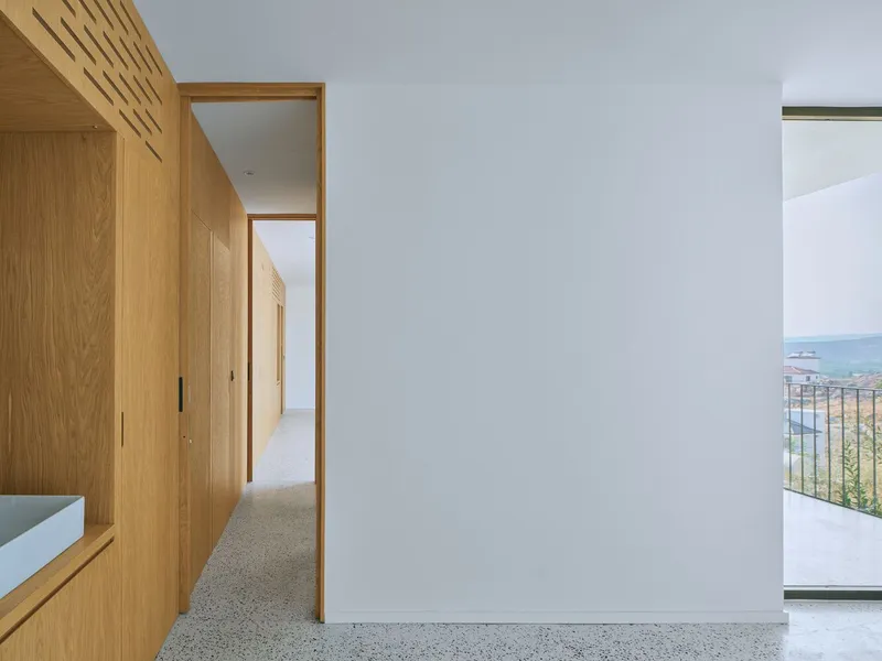 Corridor with terrazzo flooring framed by oak millwork and white walls opening to exterior terrace
