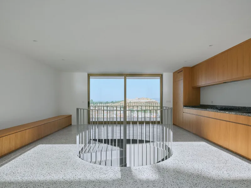 Kitchen with oak cabinetry and circular stairwell surrounded by metal balustrade overlooking hillside view