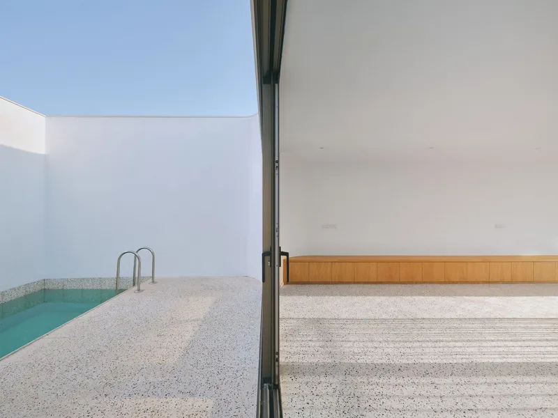 Sliding glass door connecting interior living space with terrazzo flooring to exterior courtyard pool