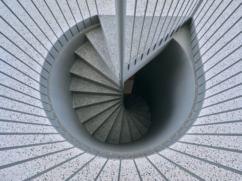 Top-down view of spiral staircase with terrazzo treads and steel railing radiating from central pole