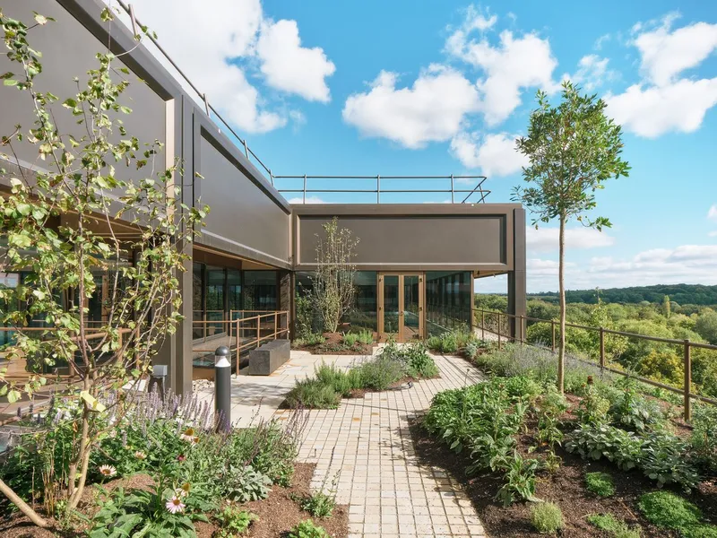 Rooftop terrace with brick paving and planted beds framed by a metal canopy structure