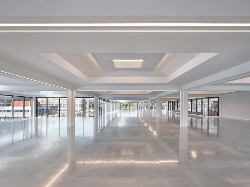 Open floor plan with white columns and coffered ceiling with linear lighting fixtures