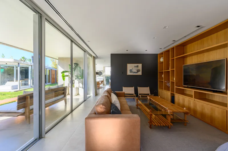 Living room with floor-to-ceiling glass doors opening to the garden and timber built-in shelving