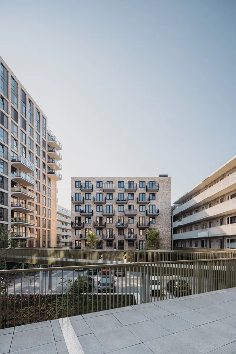 Courtyard view showing multi-story brick facades surrounding a planted terrace with vertical timber screening at ground level