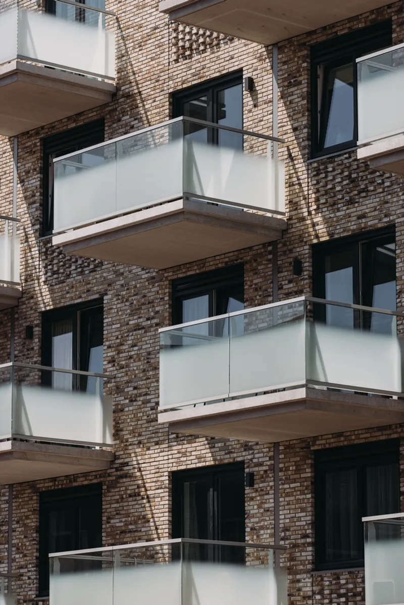Stacked balconies with frosted glass railings set into a patterned brown brick facade