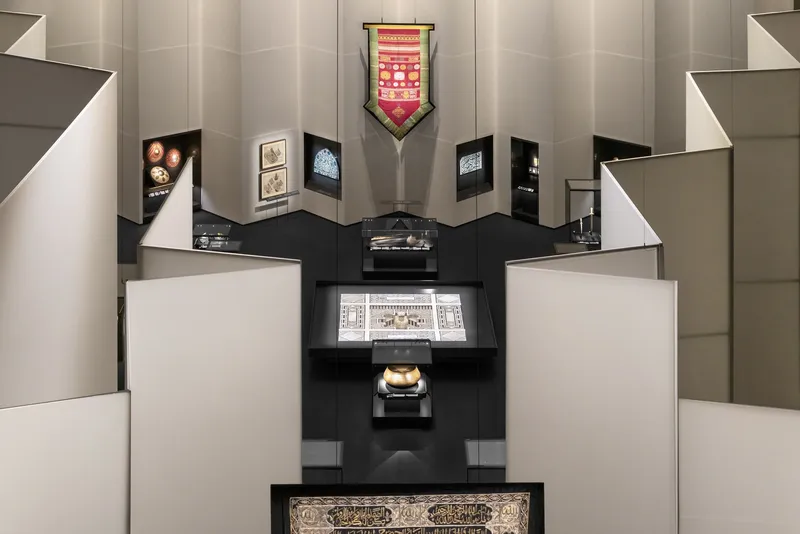 Axial view into alcove with stepped black display platforms set against folded white partition walls