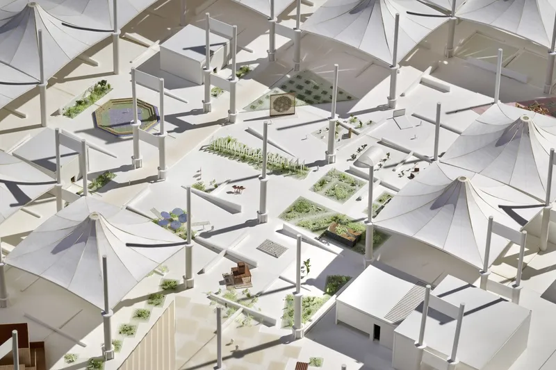 Aerial view of a site model with tensile canopy structures and planted landscape beds in bright daylight
