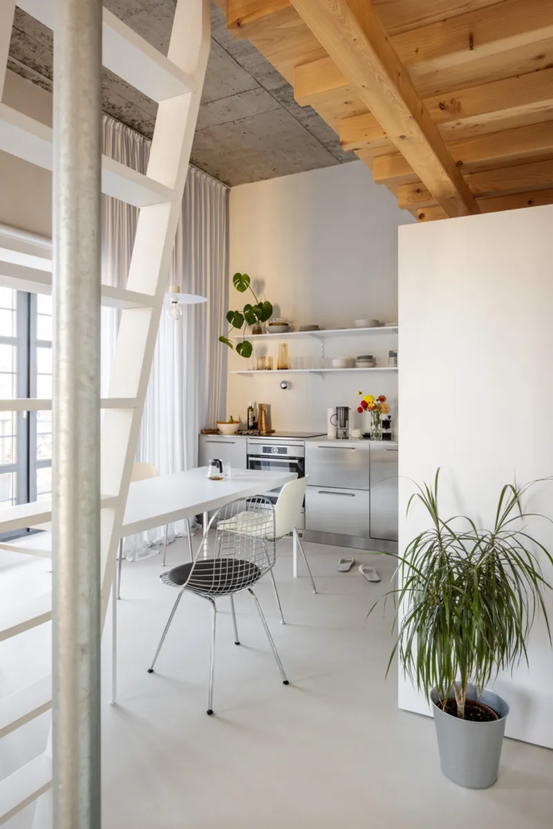 Open kitchen and dining area with exposed concrete ceiling and timber joists above