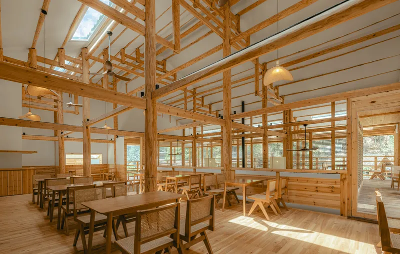 Interior dining space with exposed timber post-and-beam framework and woven cane chairs in warm afternoon light