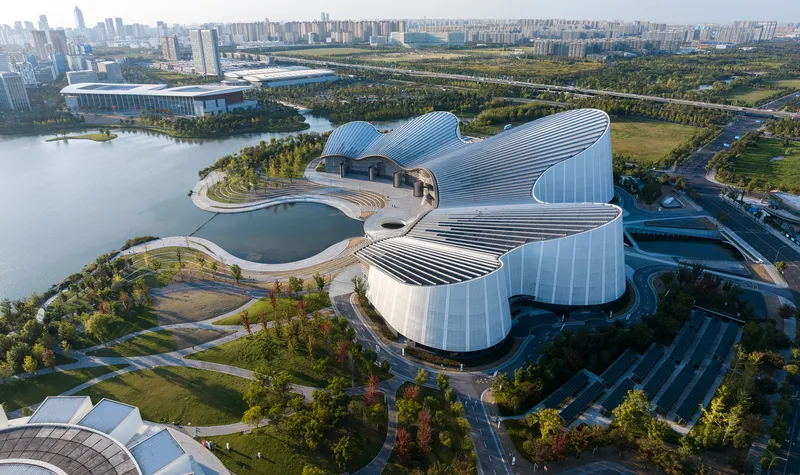 Aerial view of the ribbed metal cloverleaf roof surrounded by landscaped paths and water features