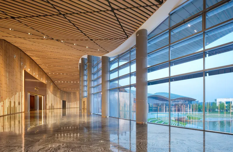 Lobby with horizontal wood slat ceiling and floor-to-ceiling glass walls overlooking a reflecting pool