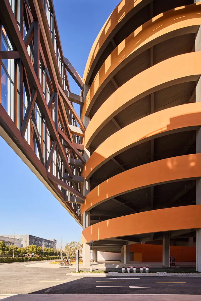 Corner junction where orange curved balconies meet an open-frame structural screen under clear sky