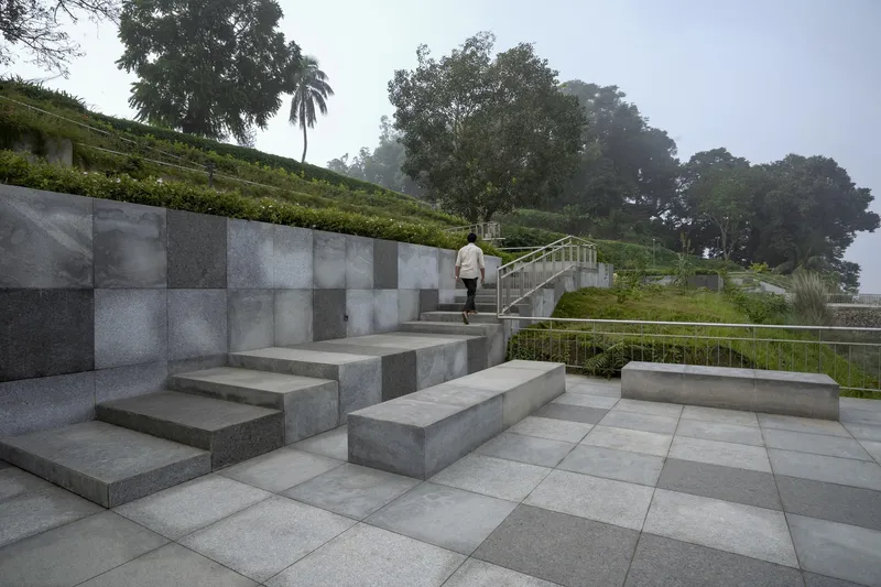 Terraced concrete amphitheater with chequered stone panel wall and person ascending the steps in morning mist