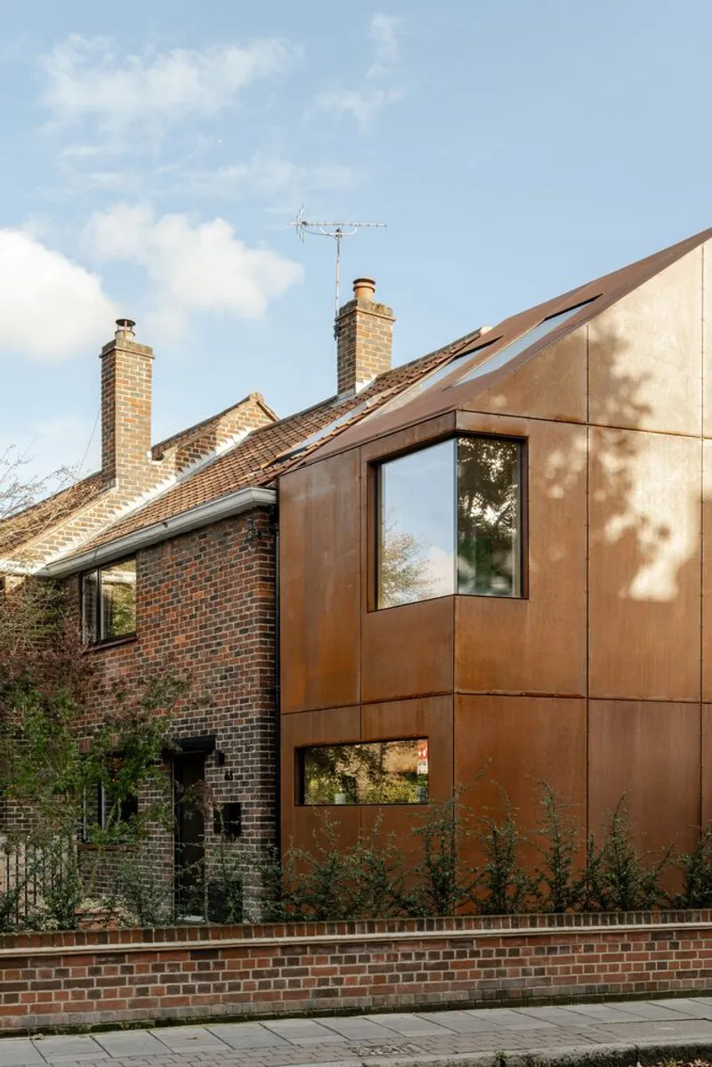 Corner detail of the paneled copper facade with windows reflecting tree shadows in afternoon light