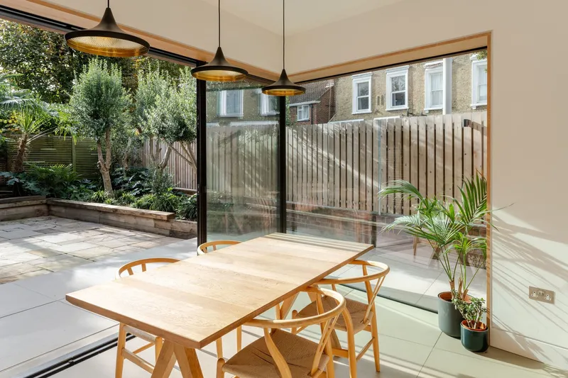 Dining room with sliding glass doors opening to garden and timber fence beyond