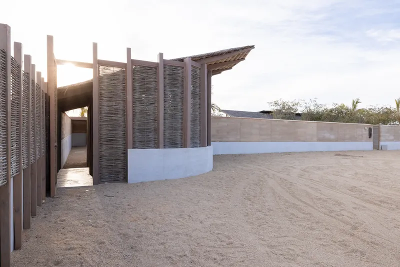 Pavilion with slatted timber screens on white plinth base and angled roof at sunset