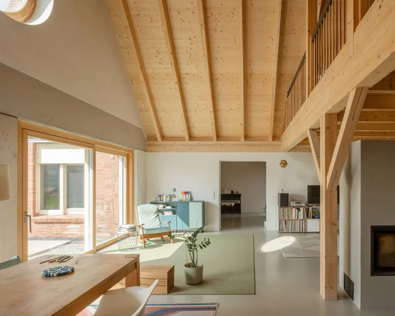Double-height living space with exposed timber rafters and a timber mezzanine overlooking the interior