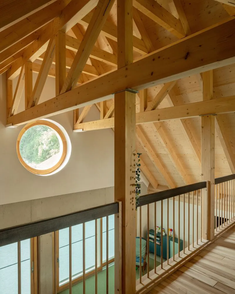 Interior view showing exposed timber framing and a circular window above the wooden balustrade