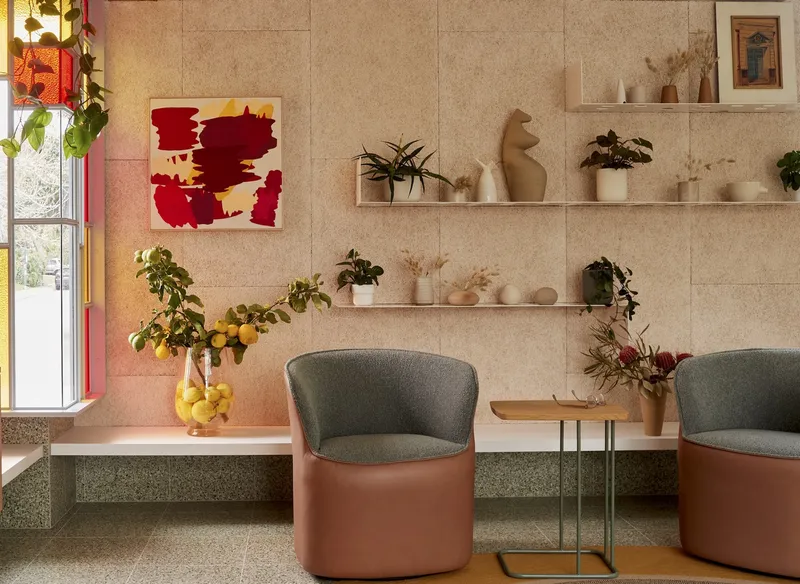 Banquette seating with leather-wrapped chairs and floating shelves displaying plants against cork tile walls