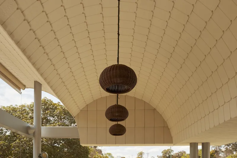 Barrel vaulted ceiling with cream shingle cladding and three woven pendant lights hanging in sequence