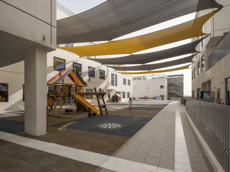 Central courtyard with timber play structure under yellow and grey fabric shade canopies