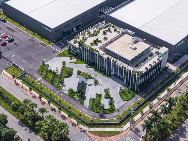 Aerial view of the stepped concrete volume surrounded by courtyard gardens and adjacent industrial buildings