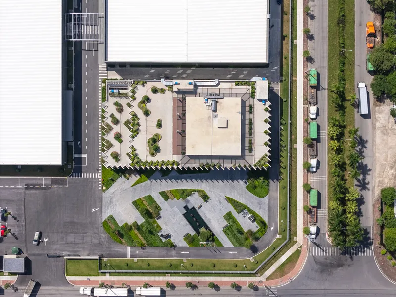 Overhead view of the corner site showing landscaped plaza and vertical fin facade beside the street