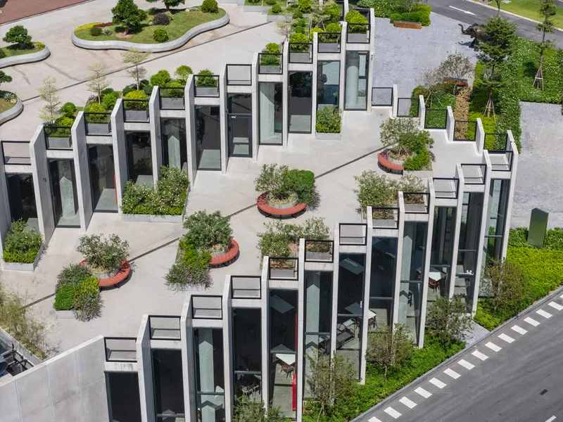 Aerial view of sawtooth roofline with rooftop gardens and circular tree planters in concrete paving