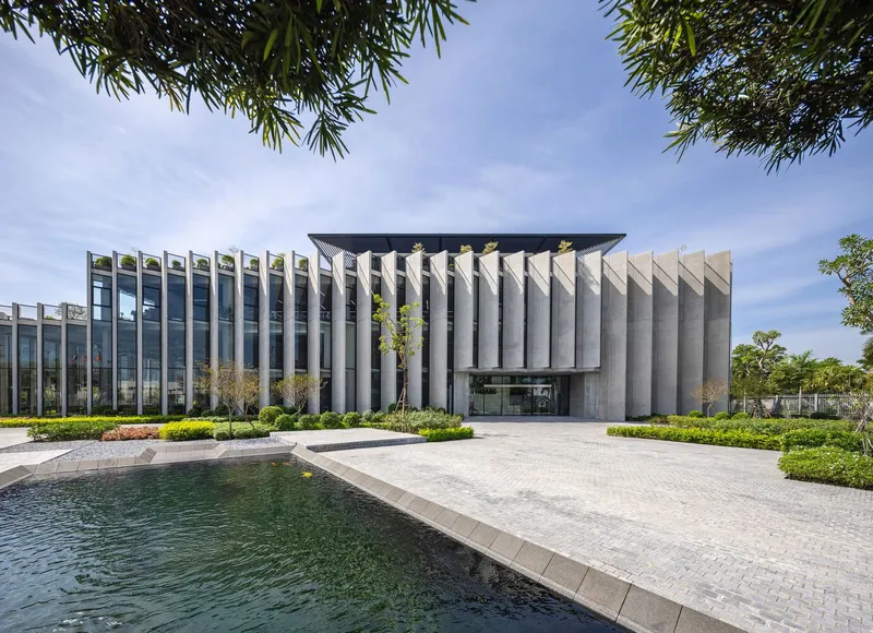 Main entrance with sawtooth concrete facade rising from a reflecting pool and paved forecourt