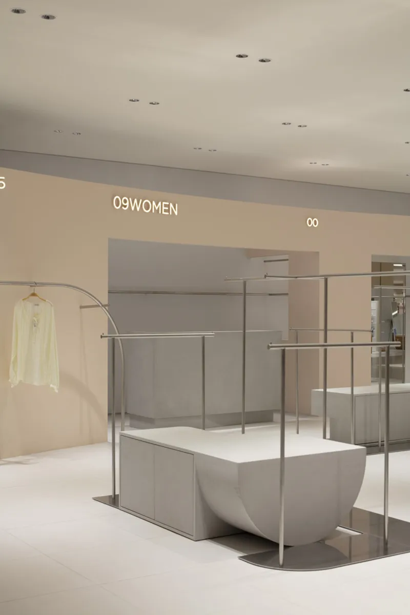 Display fixture with curved steel rail and white garment beside numbered alcoves