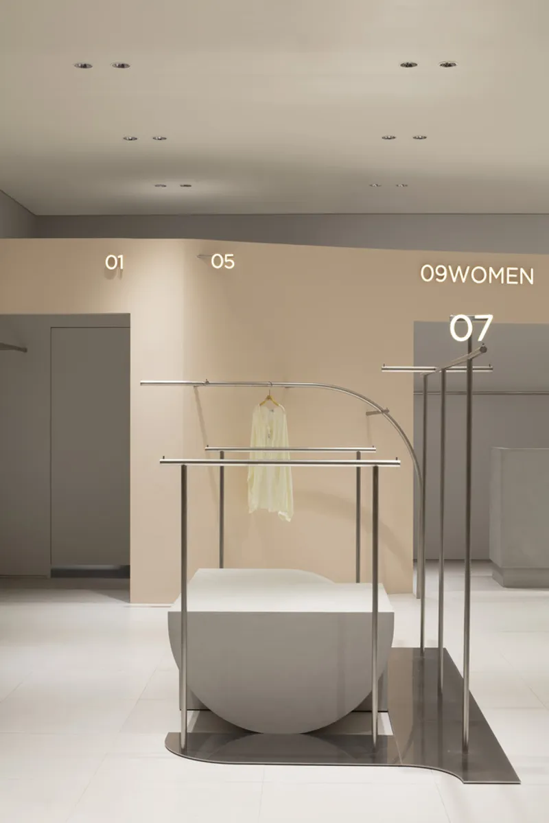 Arched steel clothing rack with concrete plinth near numbered wall signage