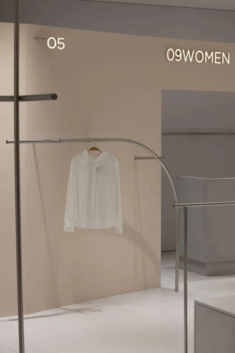 Curved metal clothing rail with a single white shirt on a wooden hanger in soft ambient light
