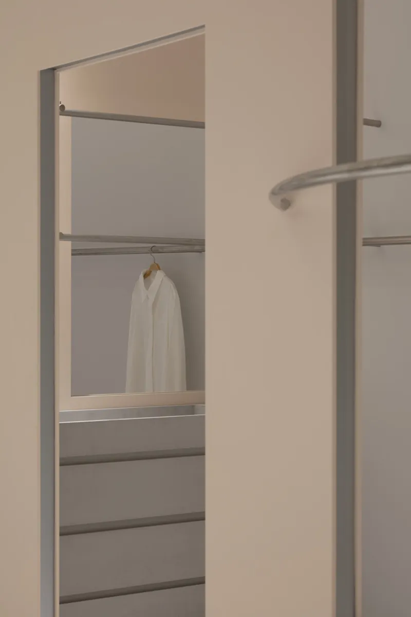 Doorway framing a view into a fitting room with tiered metal rails and horizontal shelving